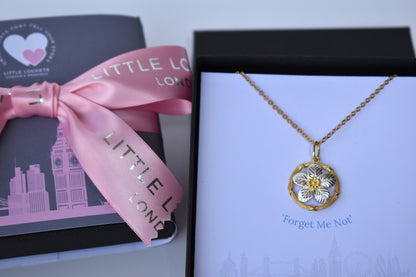 Sterling silver and gold plated forget me not pendant.  A delicate forget me not with sterling silver petals encased within a gold plated circle. Matching stud earrings. Necklace is shown in presentation gift box with the words "Forget me not" immediatlely underneath the pendant.