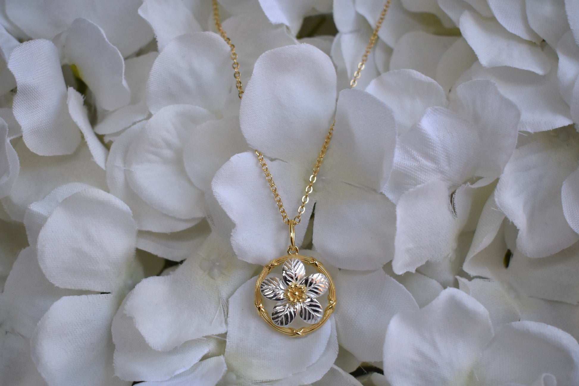 Sterling silver delicate forget me not flower with gold plated centre and circle surround. Suspended from a gold plated chain.