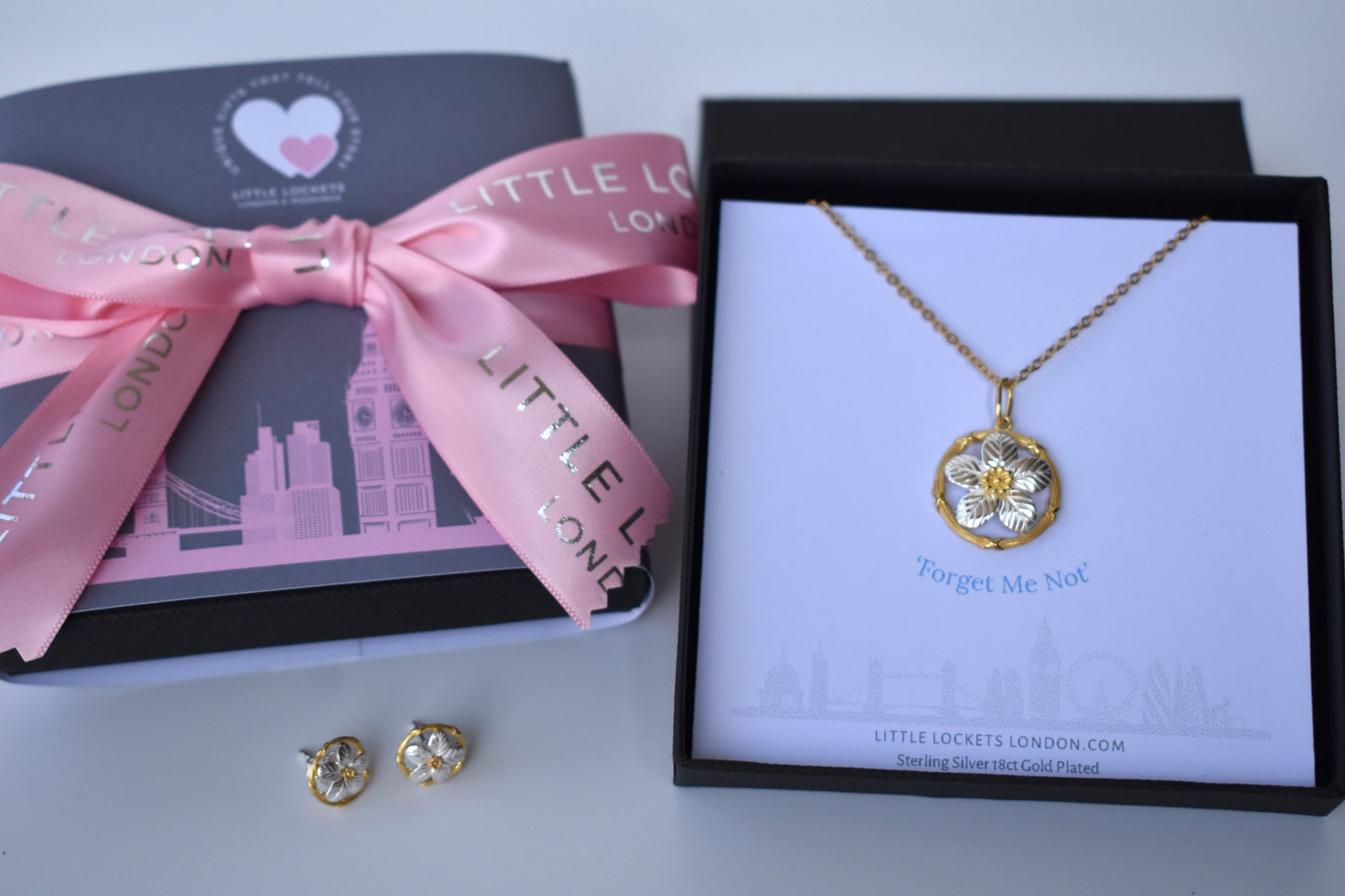 Sterling silver forget me not pendant with gold plated centre and surrounding circle. Presented in a branded gift box with the words "Forget Me Not" placed immediately underneath the pendant. Shown with option London wrap and ribbon tie.