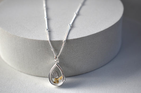 Sterling silver pear-shaped glass locket with tiny heart and key charms on a beaded chain