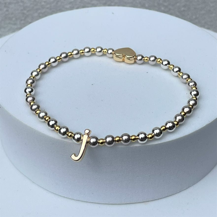 Gold and silver plated beads surround a gold colour lower case initial which sits opposite a gold plated heart, to form this stacker bracelet.