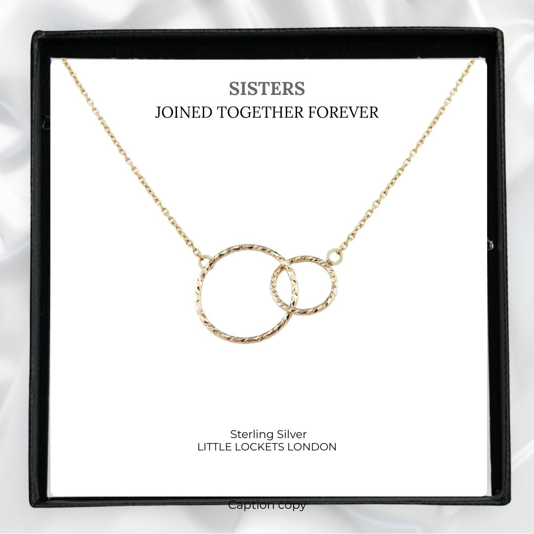 Entwined gold circles shown in gift box with the message "Sisters, joined together forever"