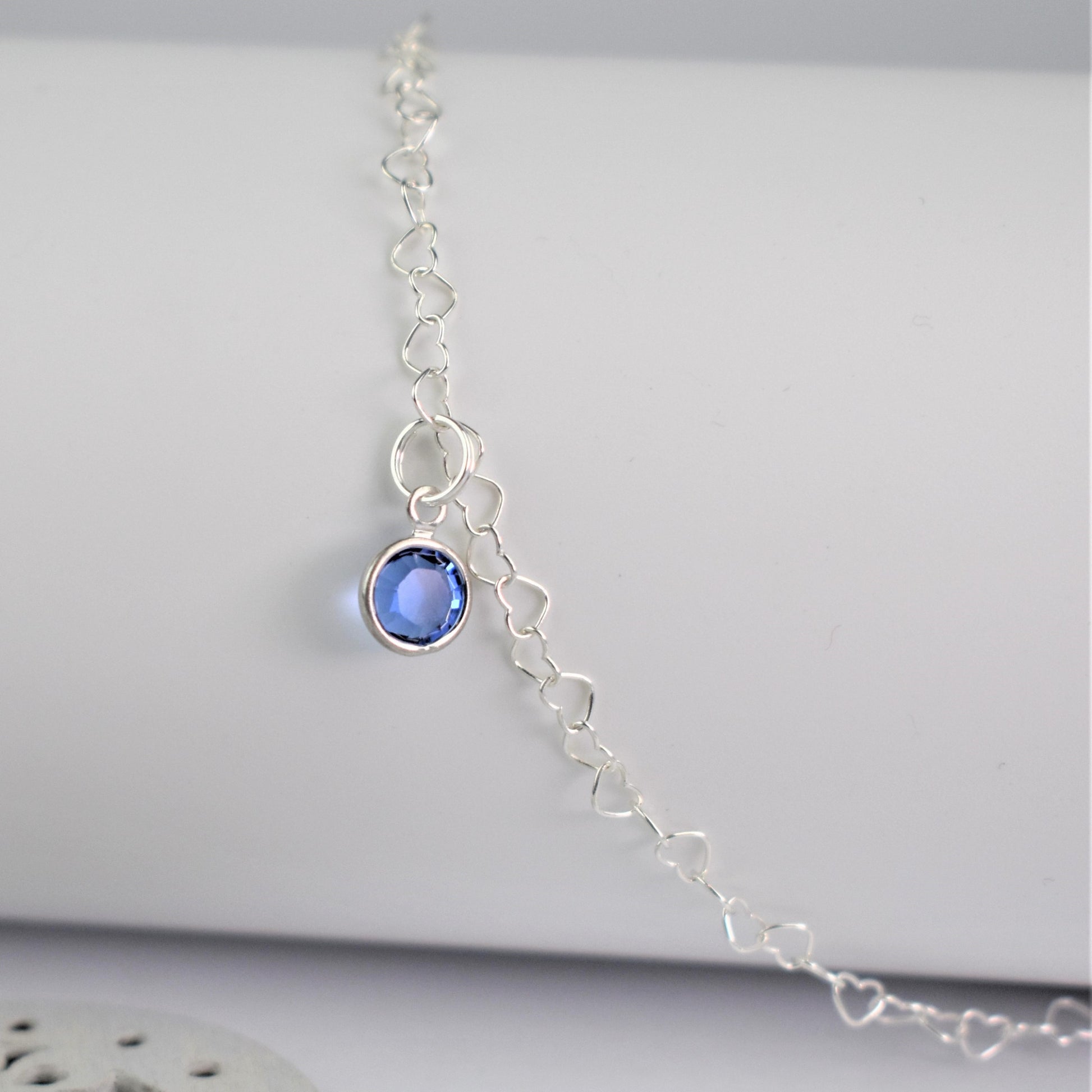 Close up of Sterling Silver heart link anklet with something blue sapphire crystal charm