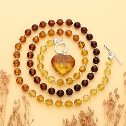 Cognac amber beads for a necklace which is fastened at the front by a sterling silver T bar. Suspended from the fastener is a cognac amber heart. 