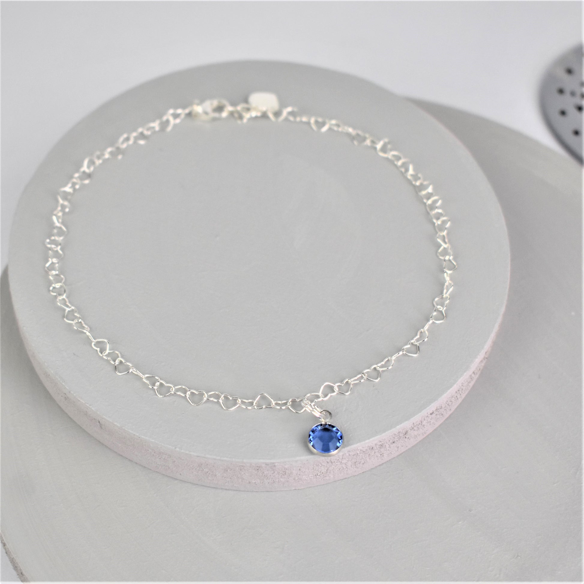Sterling silver heart shaped links form this pretty anklet hung with a tiny blue crystal. 