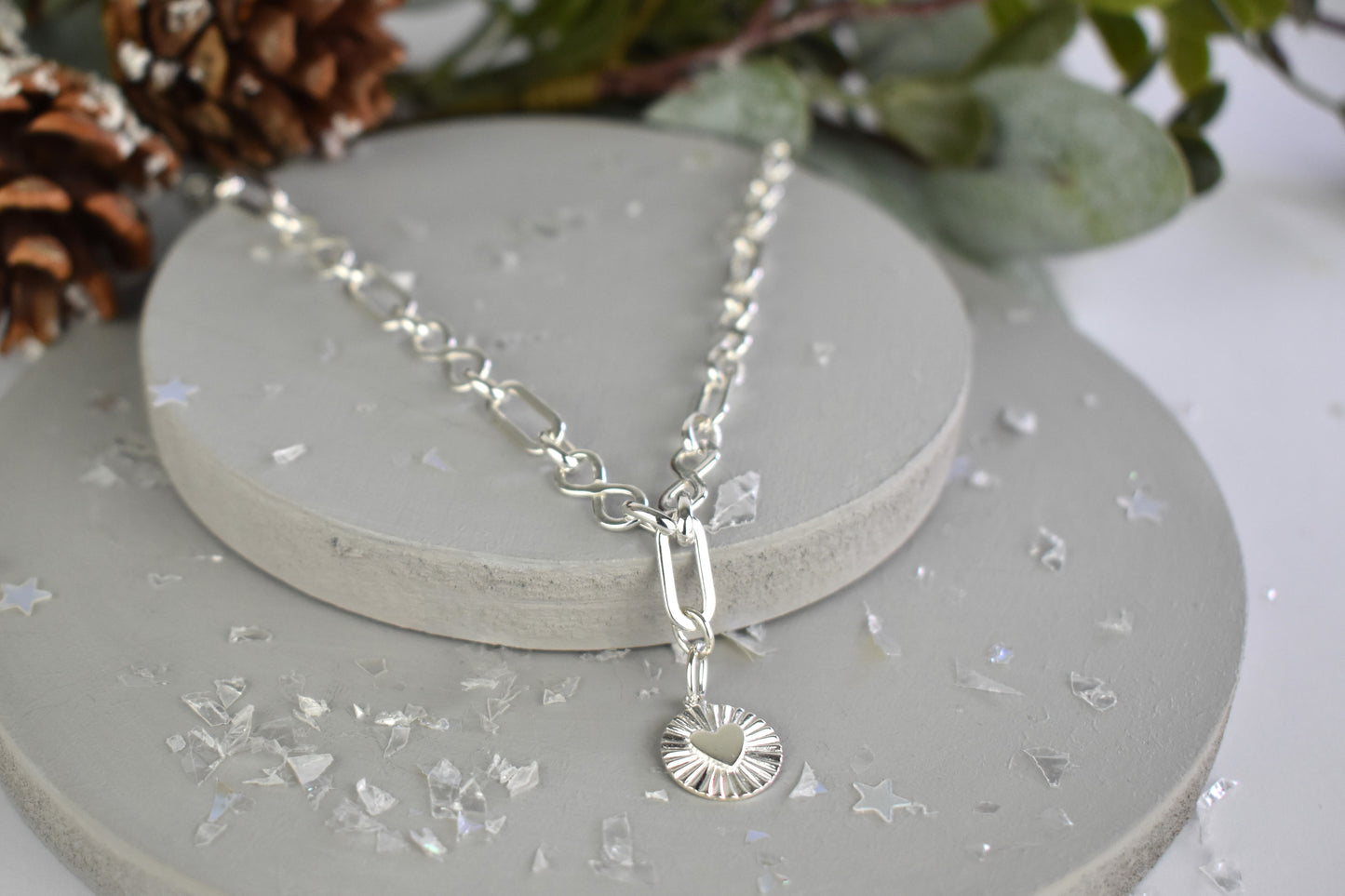 Sterling Silver Handmade Flat Link Infinity Necklace featuring a Heart Rays Pendant. Showcases flat oval and infinity links and features a Sterling Silver Sunburst Heart Rays charm pendant surrounded by an intricate sun rays design