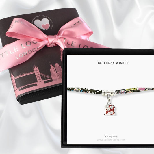 Liberty print fabric bracelet with sterling silver beads and an 18 charm in gift box with a card saying Birthday Wishes. With optional gift wrap shown in background