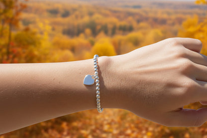 16mm heart shaped sterling silver locket suspended from 4mm sterling silver beads threaded onto strong elastic. The locket opens for you to add two photos of your choice. Shown worn