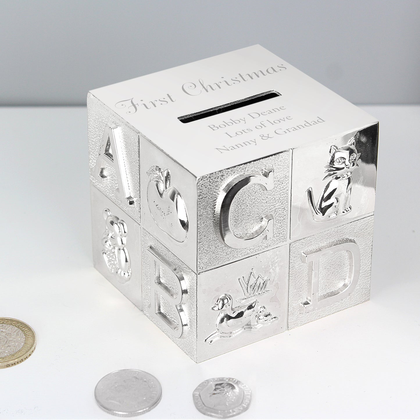 silver plated child's ABC money box. The occasion  is engraved above the money slot in a script font. Beneath the money slot, there is room for three lines of text for your own message. 