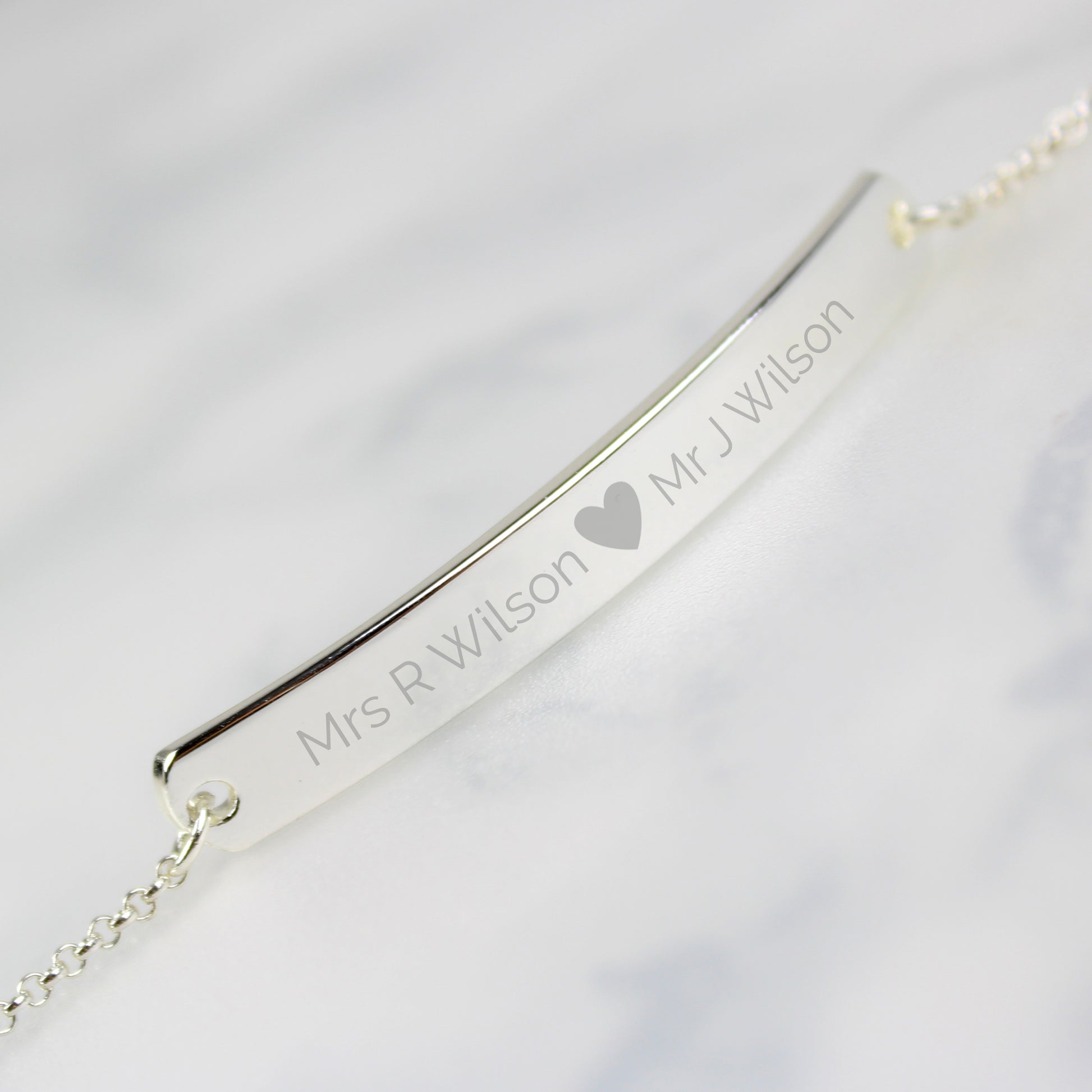 Silver colour bracelet shown with two personalised names etched on to front bar and separated by a small etched heart.. Plenty of room for your engraving!