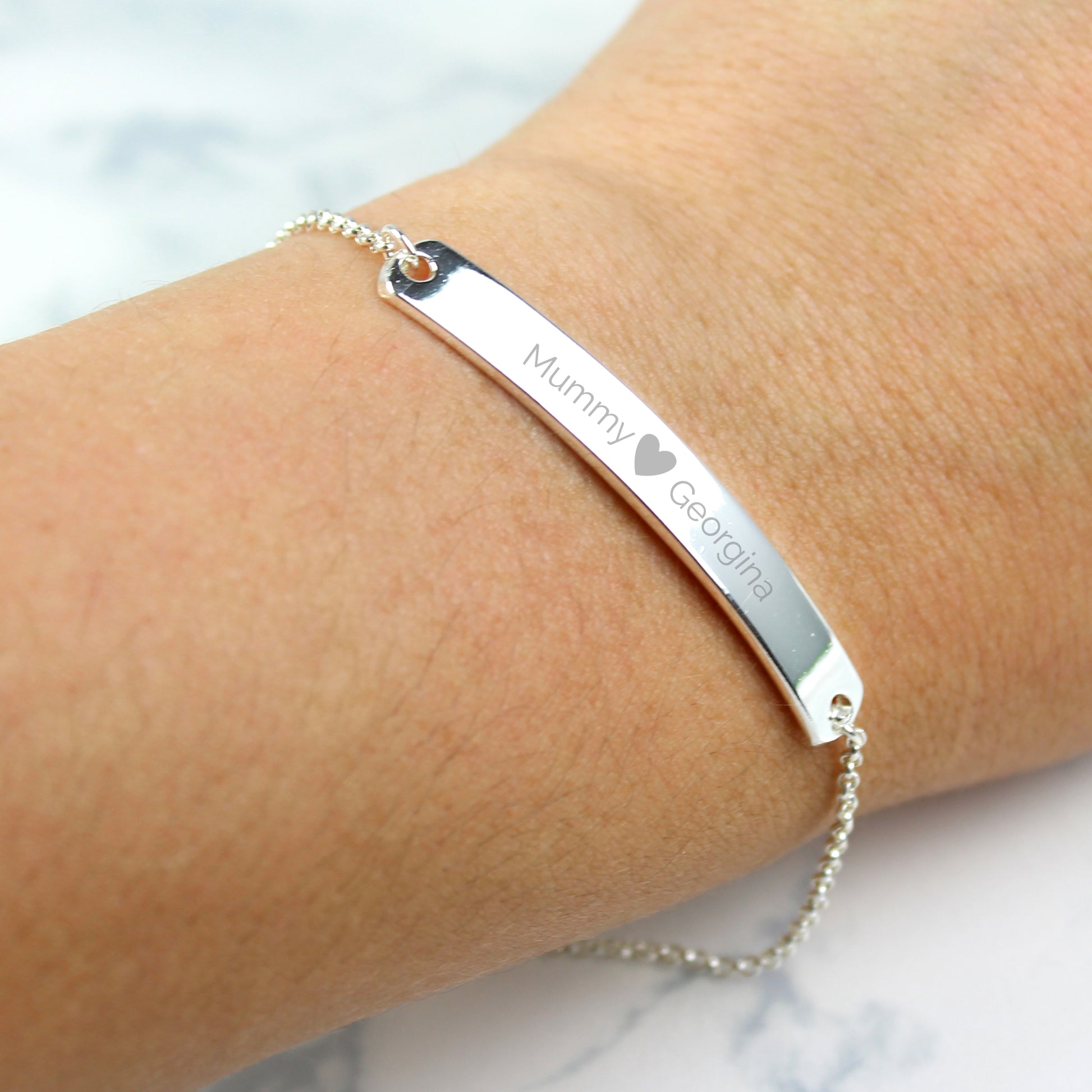 Silver colour bracelet shown with two personalised names etched on to front bar and separated by a small etched heart. Not just couples, this one shows the names of a mother and daughter.
