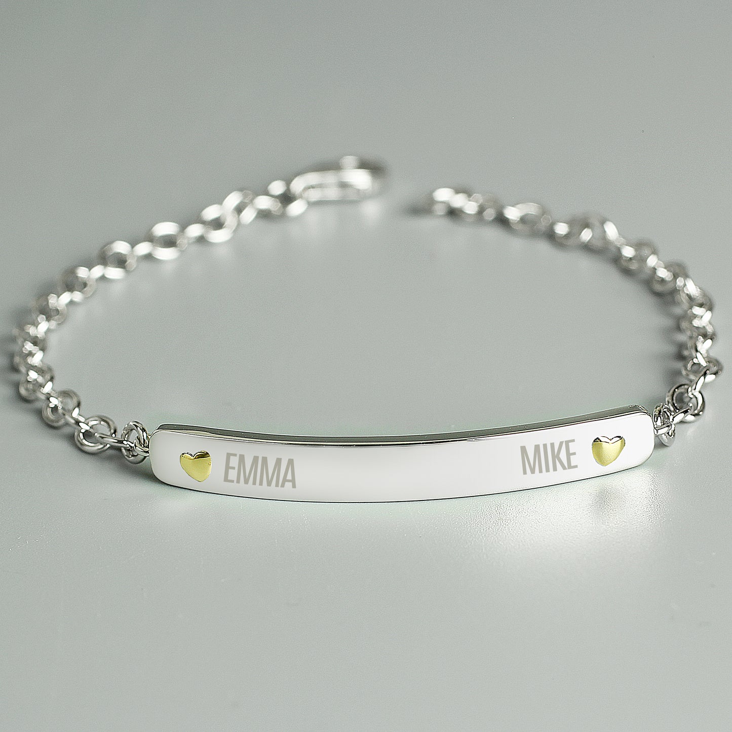 sterling silver bracelet engraved with two names and a tiny gold plated heart beside each