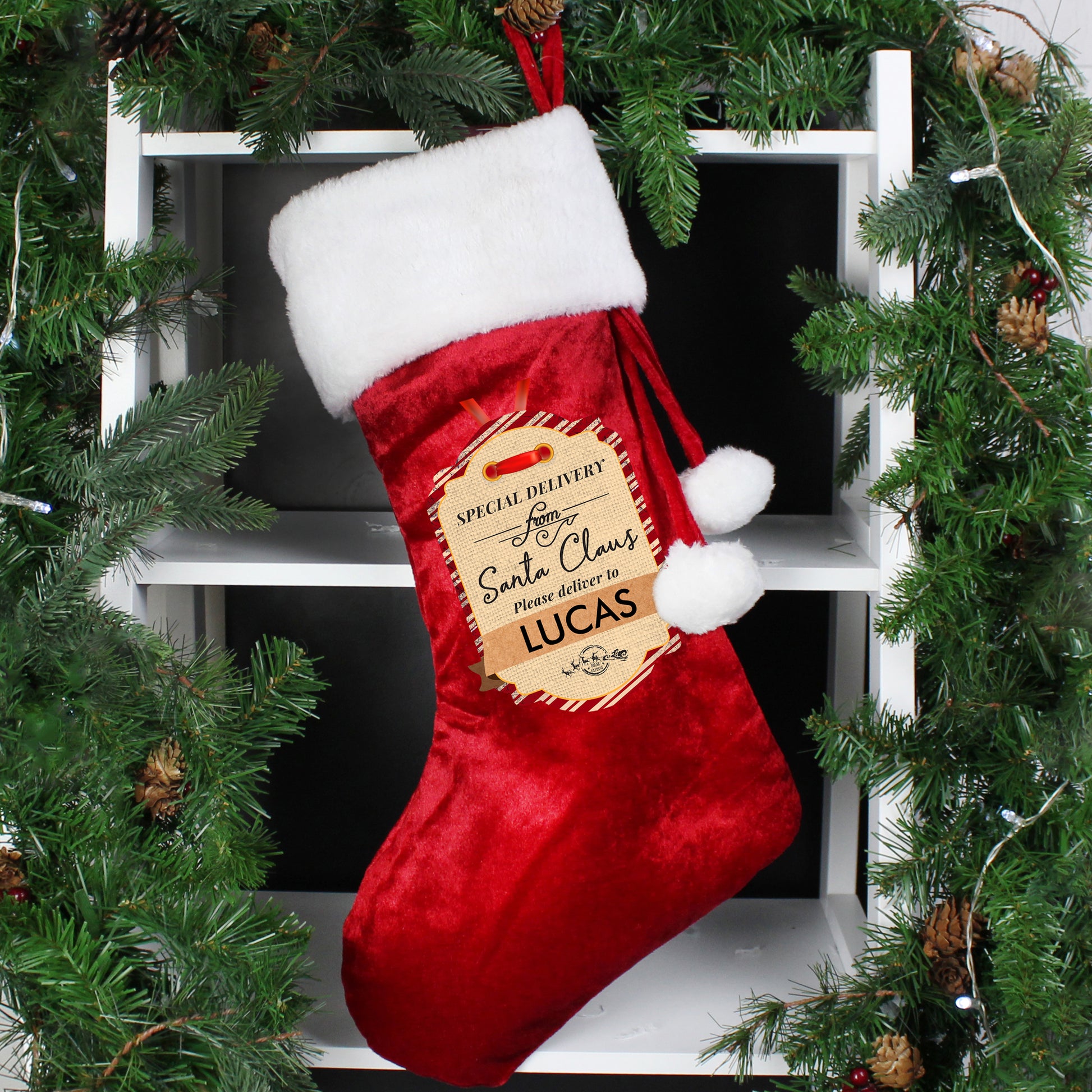 Christmas stocking in red velvet with white furry trim, fastened with a thanging ribbon finished with white pompoms. The sock has a printed "Special delivery from Santa Claus" tag the line "please deliver to" and room for a child's name.