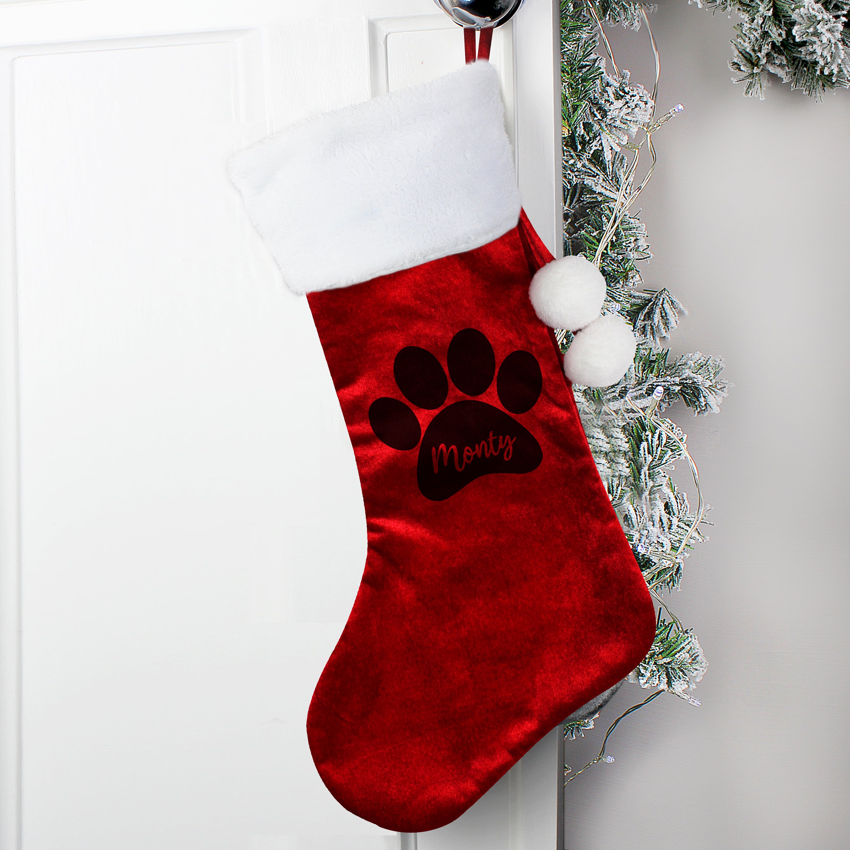 Red velvet Christmas stocking trimmed with whie fur and finished with two white pompoms. There is a paw print on the stock and space within it to add your pet's name. 