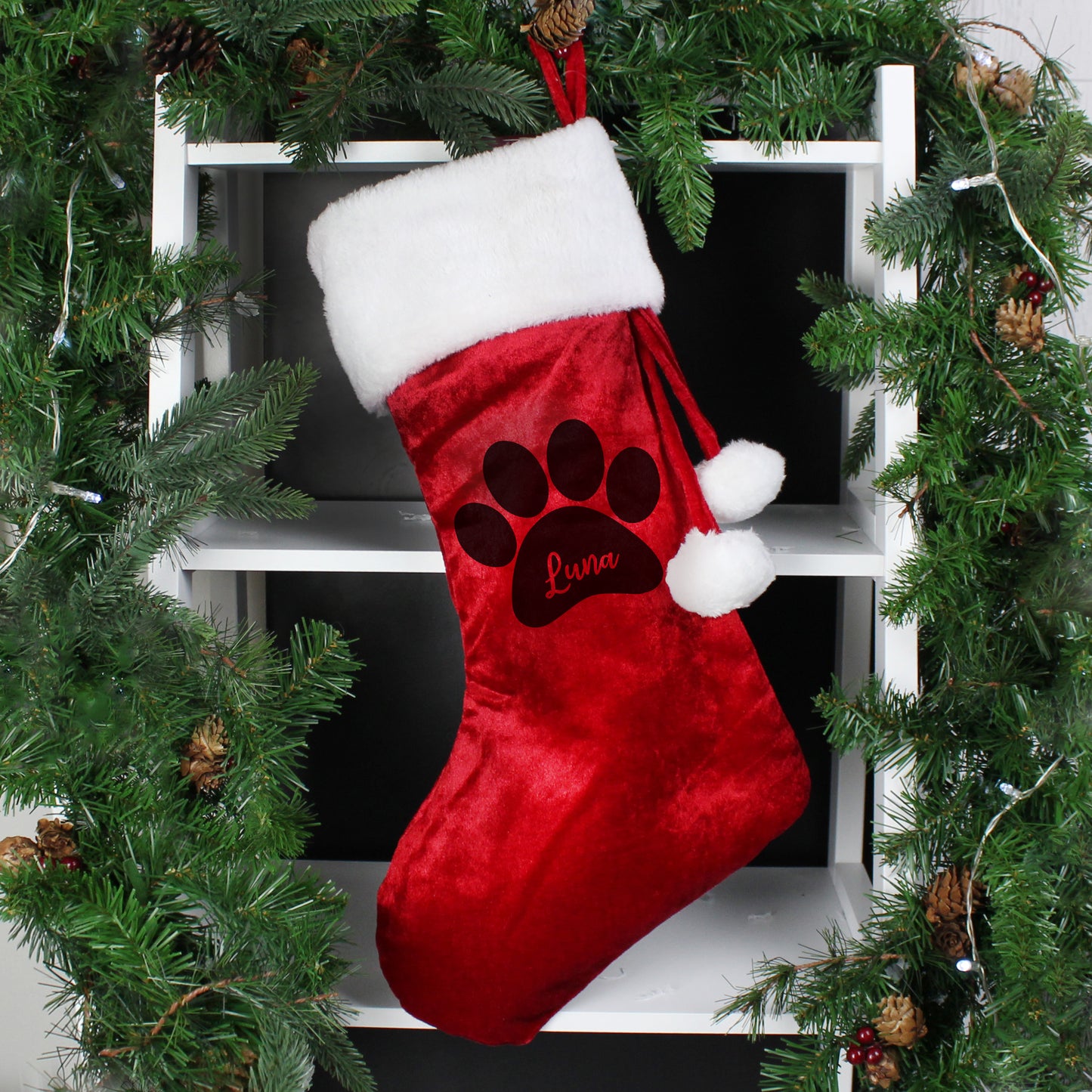 Red velvet Christmas stocking trimmed with whie fur and finished with two white pompoms. There is a paw print on the stock and space within it to add your pet's name. 