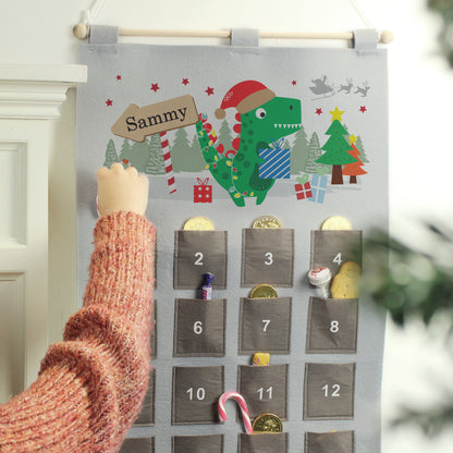 Felt advent calendar with cartoon dinosaur illustration and candy stripe sign personalised with a child's name 