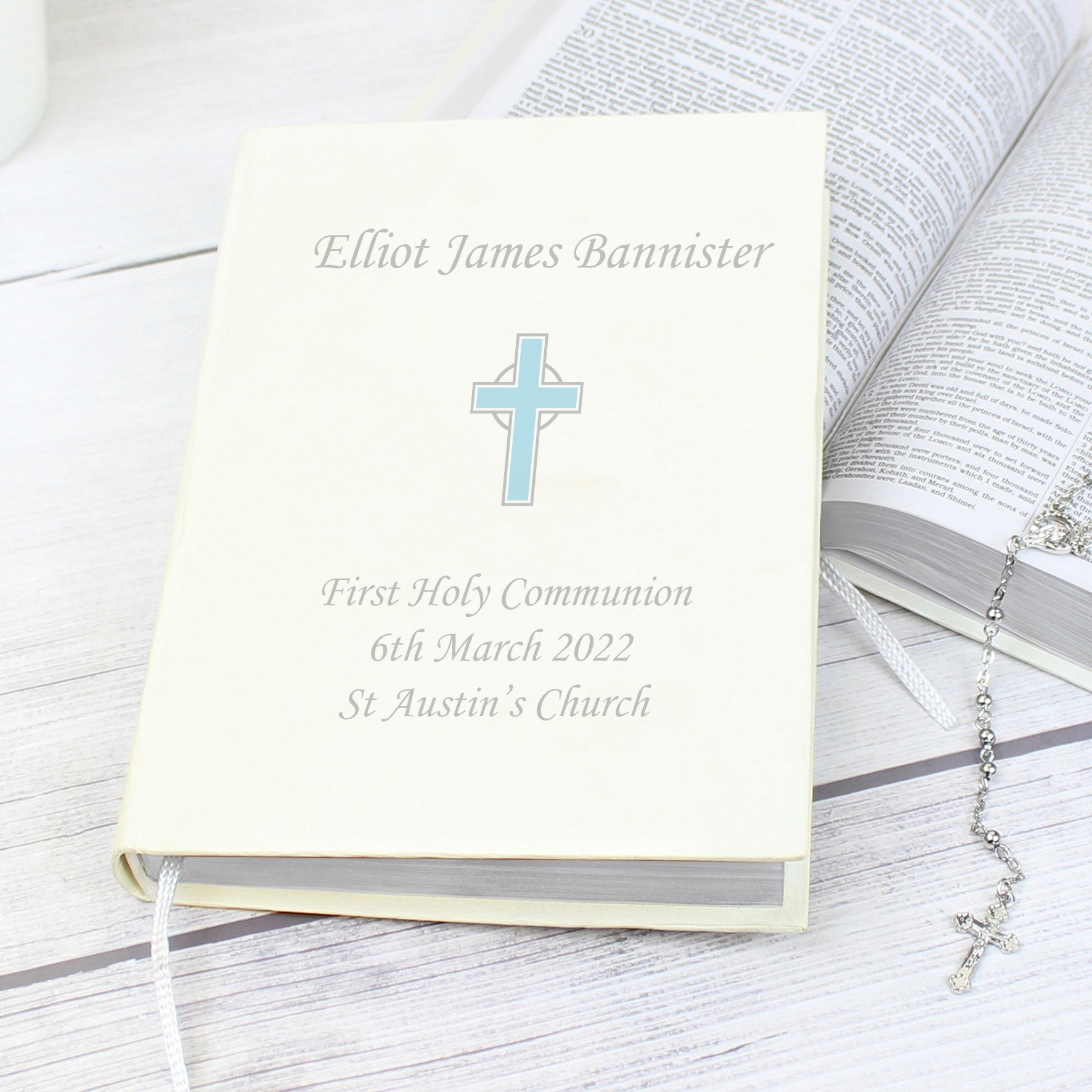 White faux leather King James Bible with blue cross and up to four lines of personalised text. Bible has one ribbon bookmark.