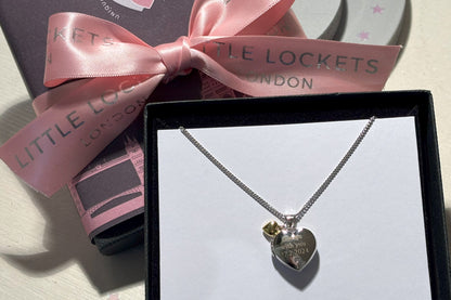 sterling silver heart shaped locket with engraved message and tiny gold heart, close up view