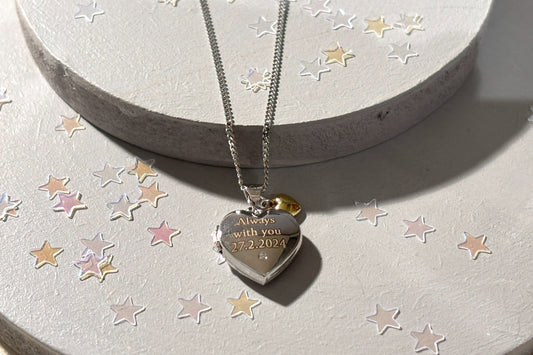 sterling silver heart shaped locket with engraved message and tiny gold heart, close up view