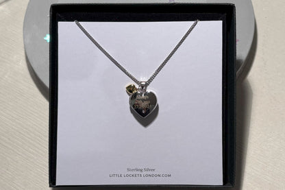 sterling silver heart shaped locket with engraved message and tiny gold heart, close up view