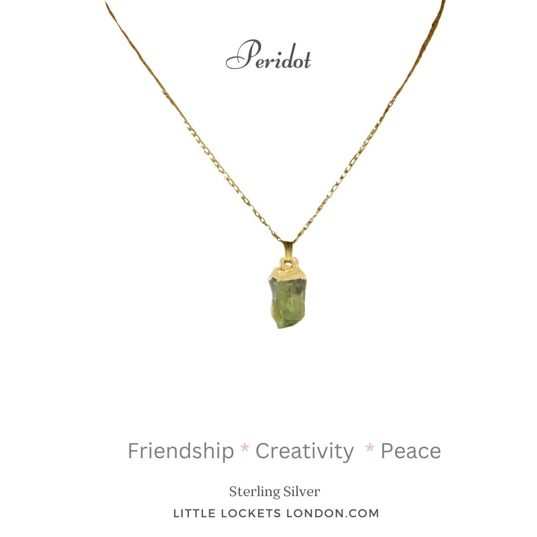 Peridot raw crystal gem with sterling silver gold plated tip suspended on sterling silver gold plated chain. Mounted on card with  the name of the gem and the three qualities - friendship, creativity, peace. 