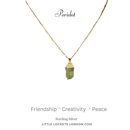 Peridot raw crystal gem with sterling silver gold plated tip suspended on sterling silver gold plated chain. Mounted on card with  the name of the gem and the three qualities - friendship, creativity, peace. 