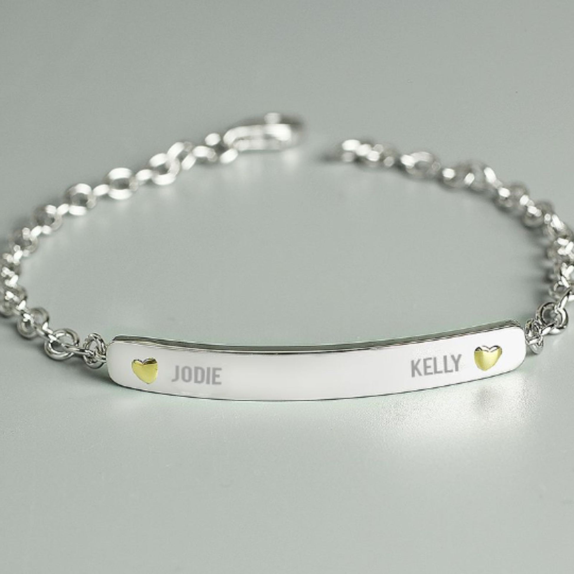 sterling silver bracelet engraved with two names and a tiny gold plated heart beside each