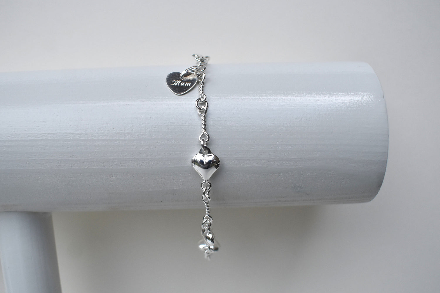 Sterling silver puffed heart and twist link bracelet showing a 10mm sterling silver heart engraved with the word "Mum". 