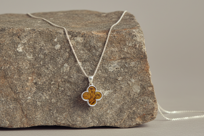 Quatrefoil-shaped pendant inlaid with genuine cognac amber. Finely textured Sterling silver edging. Pendant hangs from a sterling silver chain.