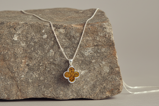 Quatrefoil-shaped pendant inlaid with genuine cognac amber. Finely textured Sterling silver edging. Pendant hangs from a sterling silver chain.