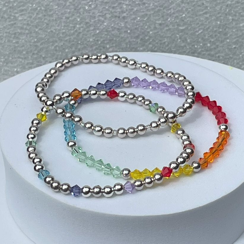Multicolour rainbow crystal stacking bracelet made up of 4mm high quality crystals interspersed with a silver plated bead. Shown with more elasticated bracelets from our Stackers collection.