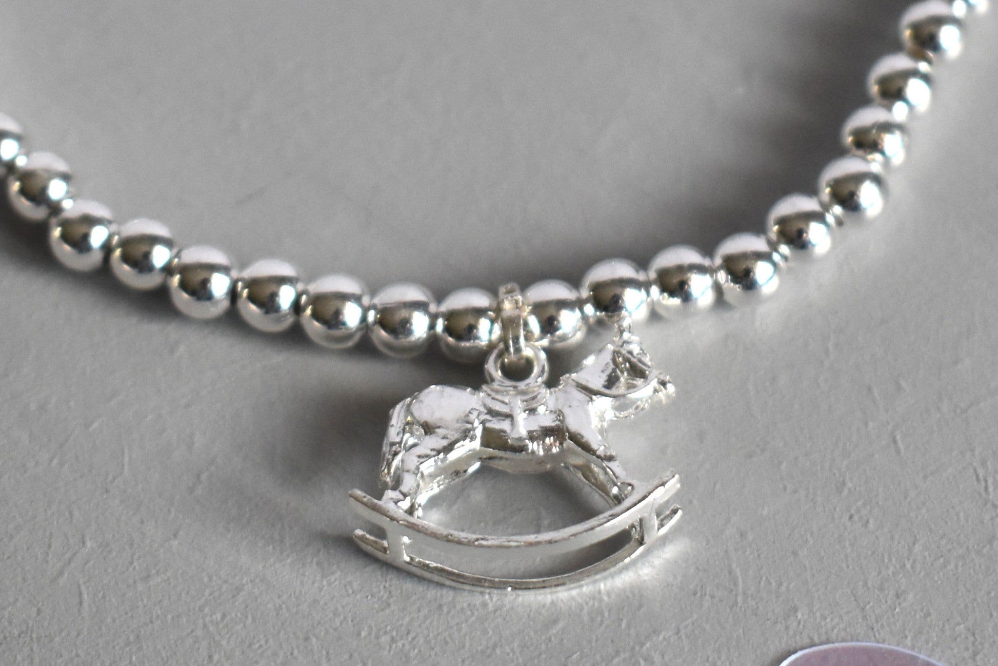 Close up of Silver bracelet with a rocking horse charm