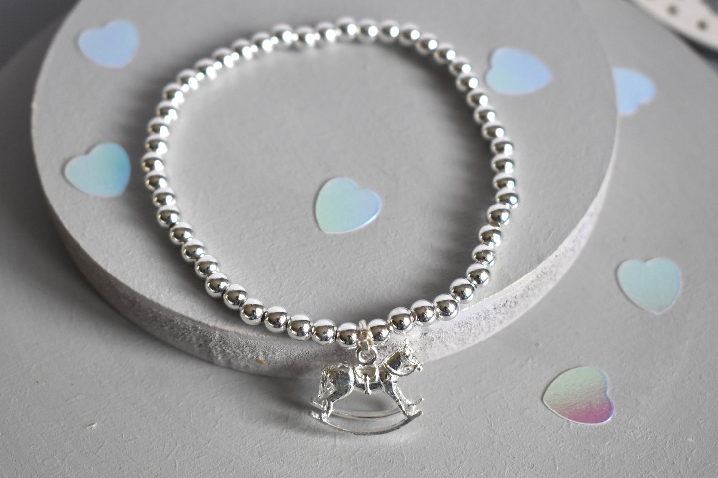 Sterling silver rocking horse charm suspended from a sterling silver beaded bracelet - 4mm beads threaded onto strong elastic.