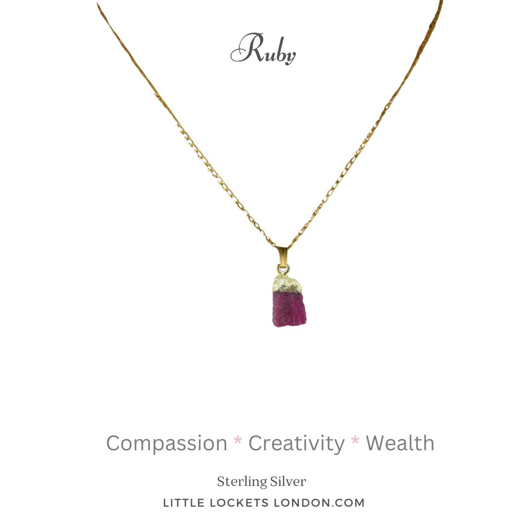 The ruby raw crystal pendant with gold plated sterling silver tip and suspended from a sterling silver gold plated chain. The pendant is mounted on card with the gem's name and three of its properties - compassion, creativity and wealth.