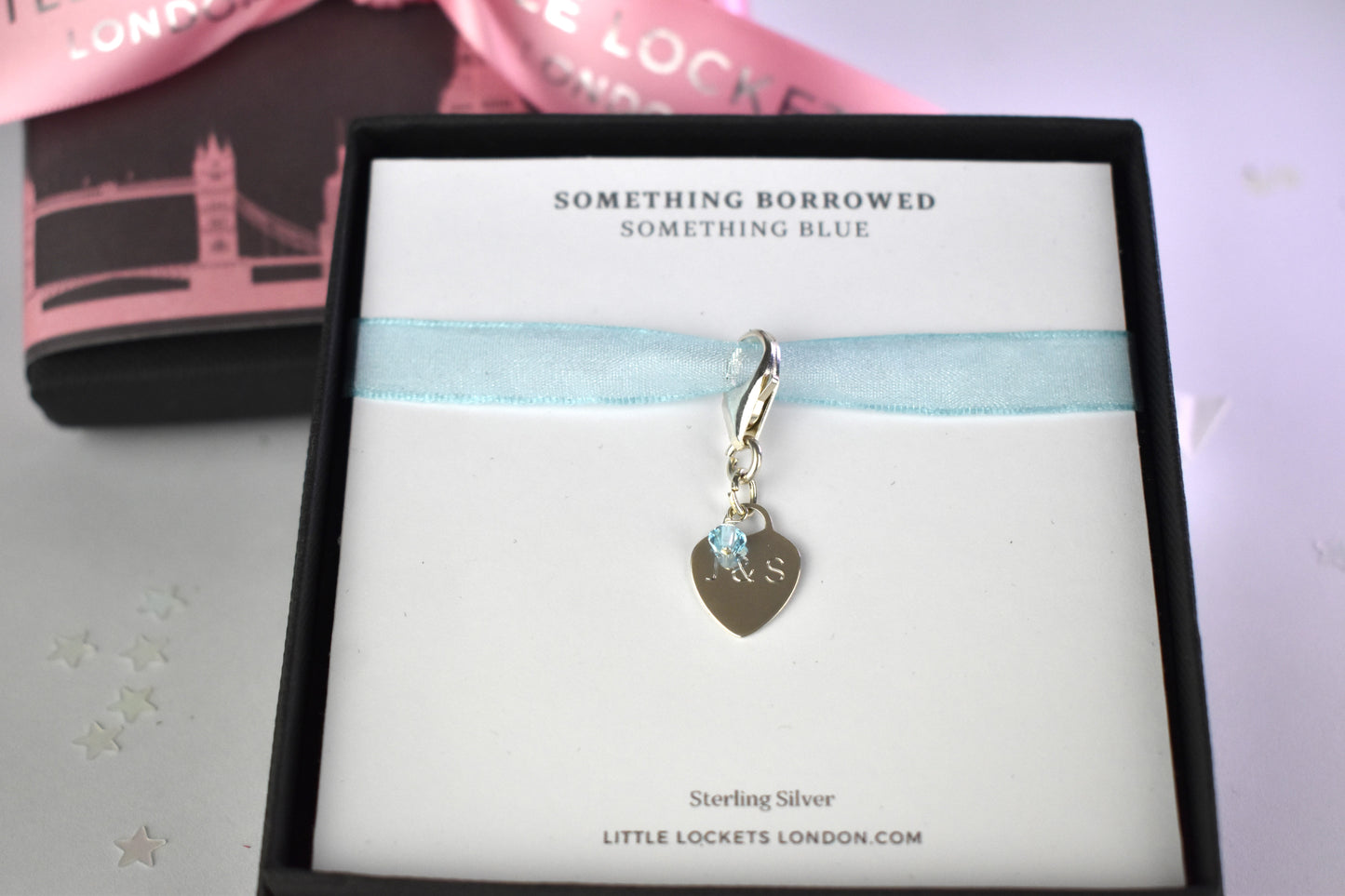 Sterling silver engraved heart and trigger clasp with tiny blue crystal shown gift boxed with card "Something borrowed, Something Blue". Optional luxury gift wrapping is shown in background. 