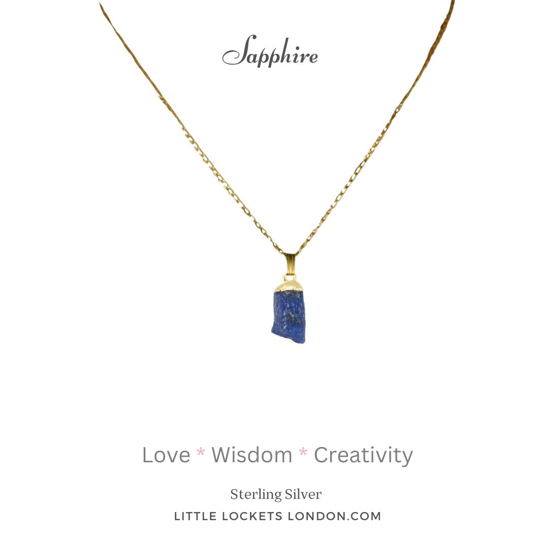 Sapphire raw crystal pendant with sterling silver gold plated tip suspended from a gold plated sterling silver chain. Mounted on card with the gem's name plus three of its properties - love, wisdom and creativity