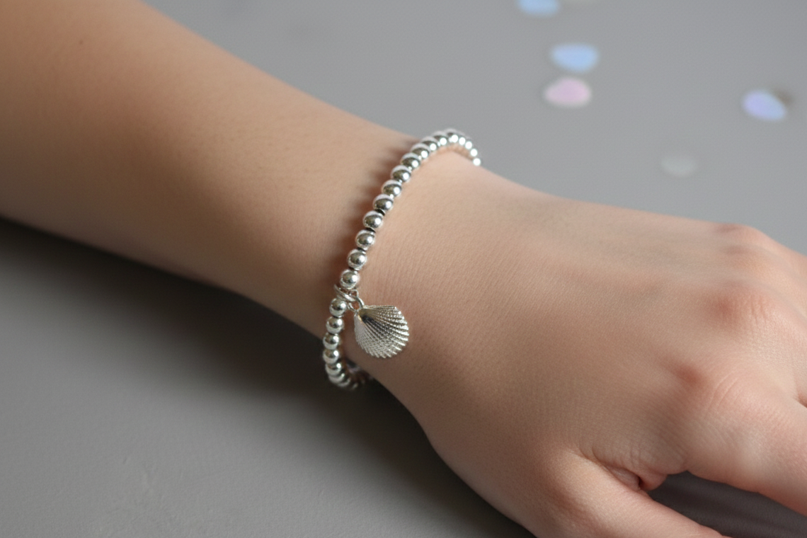 Sterling silver beaded bracelets with 4mm beads. Suspended from the bracelet  is a sterling silver clamshell. From the Ocean Collection of stacking bracelets. Shown worn