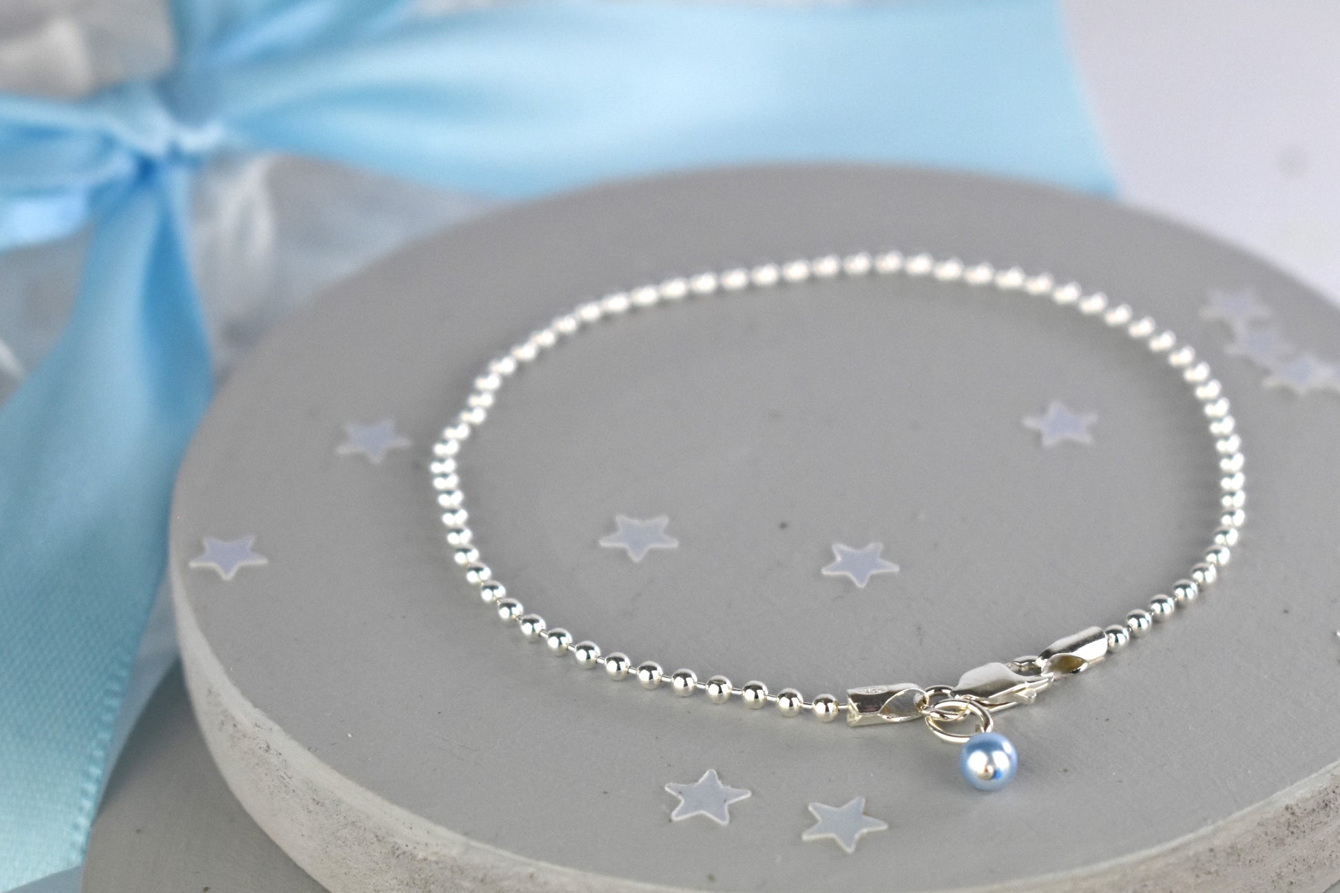 Sterling silver ball bracelet showing strong clasp and tiny blue glass pearl.