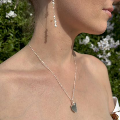 Raw Crystal Pendant. The pendant has a sterling silver tip and is suspended from a sterling silver chain. It is mounted on card with the gemstone name and three of the properties of the crystal. 