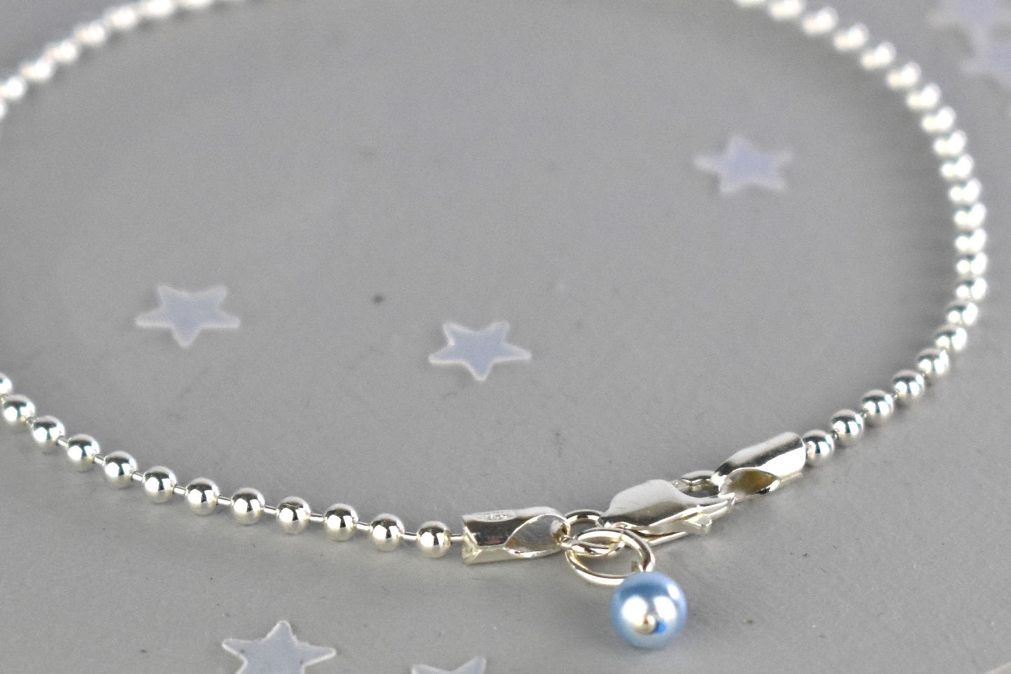 Close up of Sterling silver Something Blue bracelet with blue glass pearl charm