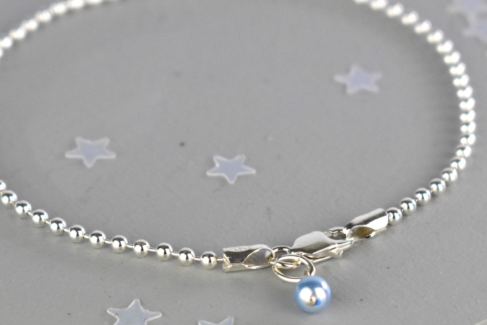 Close up of Sterling silver Something Blue bracelet with blue glass pearl charm