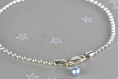 Close up of Sterling silver Something Blue bracelet with blue glass pearl charm