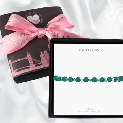 turquoise stacking bracelet shown in gift box. In the background is the upgraded gift wrap of a London skyline wrap and pink ribbon tie