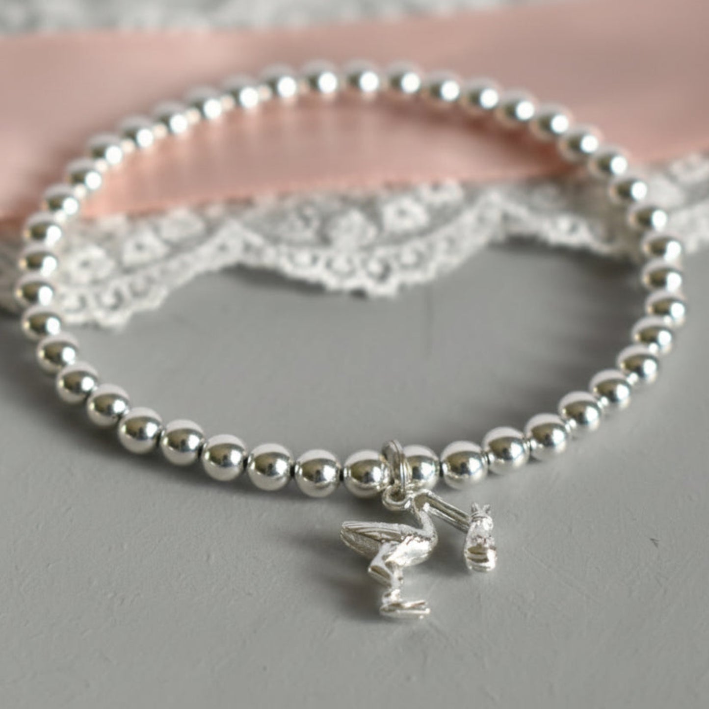 4mm sterling silver beads are threaded onto strong elastic from which is suspended a sterling silver stork carrying a little bundle. The perfect bracelet for new mums.