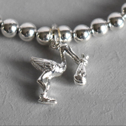 4mm sterling silver beads are threaded onto strong elastic from which is suspended a sterling silver stork carrying a little bundle. The perfect bracelet for new mums. Close up of charm