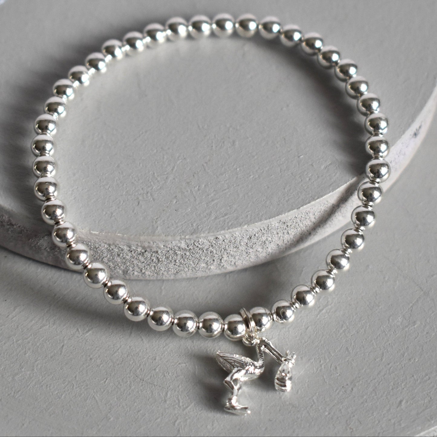 4mm sterling silver beads are threaded onto strong elastic from which is suspended a sterling silver stork carrying a little bundle. The perfect bracelet for new mums.