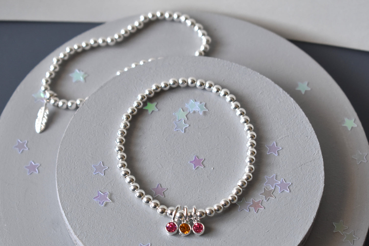 Selection of beaded stacker bracelets showing birthstones and feather charm