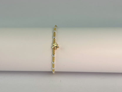 an elasticated gold and silver plated beaded bracelet with a jigsaw charm showing gold plated side
