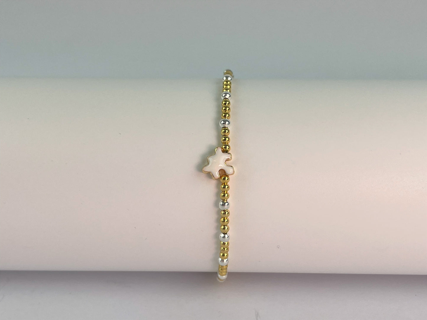 an elasticated gold and silver plated beaded bracelet with a jigsaw charm showing enamelled side