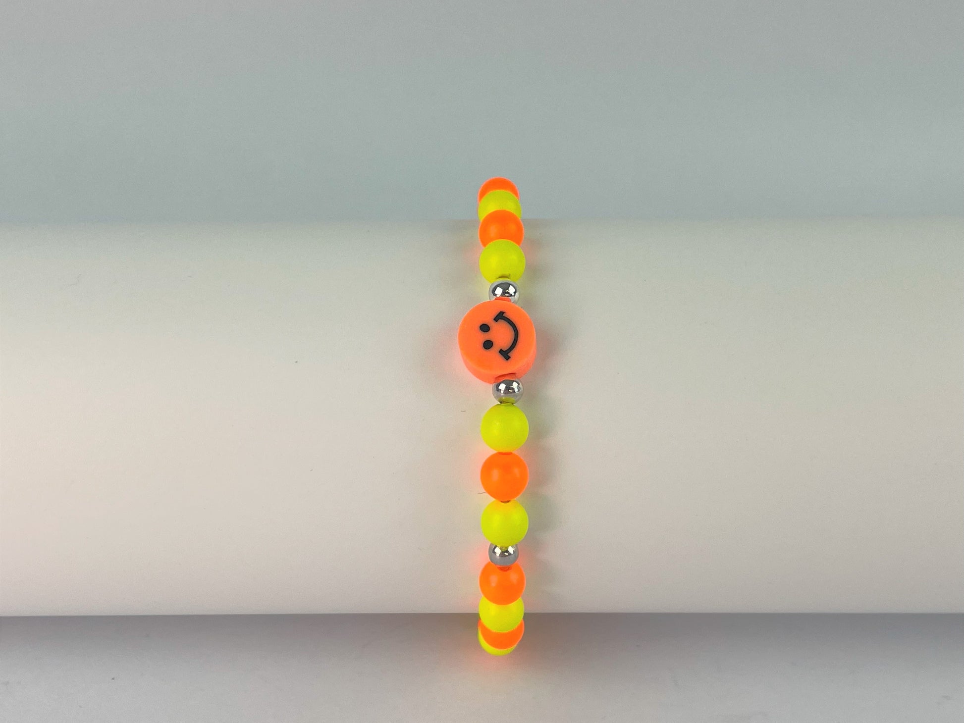 elasticated bracelet of orange and yellow neon beads with smiley face